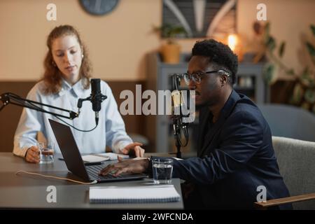 Männlicher Podcast-Host mit Laptop und Gast in Studio Stockfoto