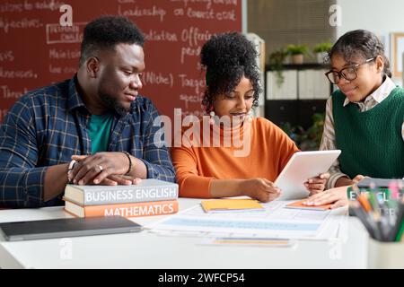 Schwarze junge Menschen verwenden digitale Tablets im College und arbeiten gemeinsam an Online-Präsentationen Stockfoto