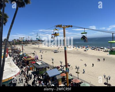 Rundblick auf Besucher, die Fahrgeschäfte und Attraktionen am Santa Cruz Beach Boardwalk genießen, mit Blick auf den Sandstrand und den Pazifischen Ozean an klaren Tagen, Santa Cruz, Kalifornien, 30. Juli 2023. Stockfoto