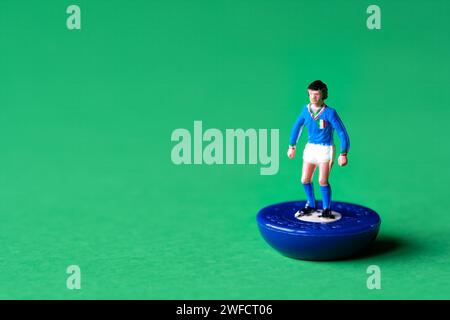Eine einzelne Subbuteo-Miniaturfigur in den Farben der italienischen Nationalmannschaft, blaues Hemd und weiße Shorts. Subbuteo ist ein Tischfußballspiel Stockfoto
