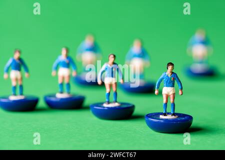 Eine Gruppe von Subbuteo Miniaturfiguren, die in den Farben der italienischen Nationalmannschaft mit blauem Hemd und weißen Shorts gemalt sind. Subbuteo ist ein Tischfußballspiel Stockfoto