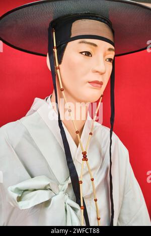 Eine Ausstellung alter, traditioneller, zeremonieller Kleidung, getragen von jemandem koreanischer Abstammung. Ein Mann in weißem Seidenmantel und schwarzem silbernem Hut. Im Centr Stockfoto