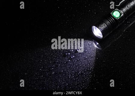 Taschenlampe wasserdicht in Tropfen auf schwarzem Hintergrund. Stockfoto