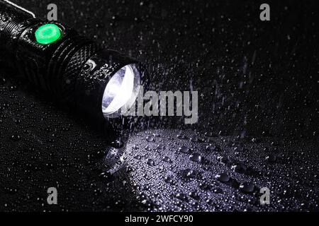 LED-Taschenlampe, wasserdicht bei Tropfen und Regen auf schwarzem Hintergrund. Stockfoto