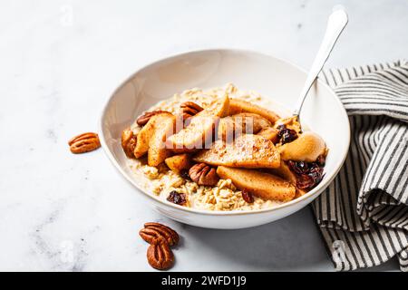 Haferflocken mit karamelisierten Äpfeln, Zimt, Pekannüssen und Preiselbeeren. Veganes Winterfrühstück. Stockfoto