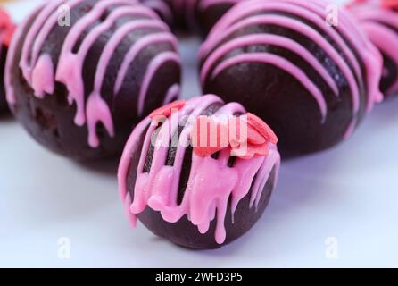 Nahaufnahme der köstlichen Schokoladenkuchen-Pops mit herzförmiger Erdbeer-Royal-Glasur Stockfoto