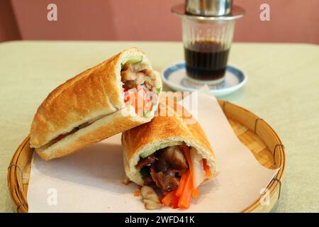 Köstliches Banh Mi mit vietnamesischem Tropfkaffee im Hintergrund Stockfoto