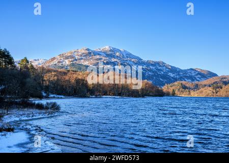 Entlang der schneebedeckten Küste von Loch Achray mit einem schneebedeckten Ben Venue, Trossachs, Stirling, Schottland Stockfoto