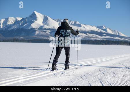 Junge Frau Skilanglauf auf einer verschneiten Wiese mit Blick auf die hohe Tatra-Kriváň. Stockfoto