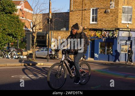 Ein Radfahrer pendelt in Hackney, East London, in der frühen Morgensonne des Winters am 26. Januar 2024, London, Großbritannien. Stockfoto