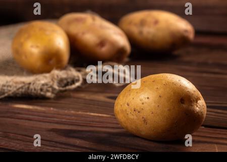 Rohe Kartoffelnahrung. Frische Kartoffeln in einem alten Sack auf hölzernem Hintergrund. Stockfoto