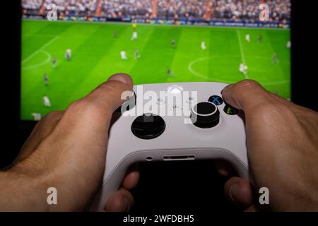 Dnipro, Ukraine, 28. september 2023: Mann spielt EA FC 24 mit Xbox-Controller auf dem TV-Bildschirm. Stockfoto