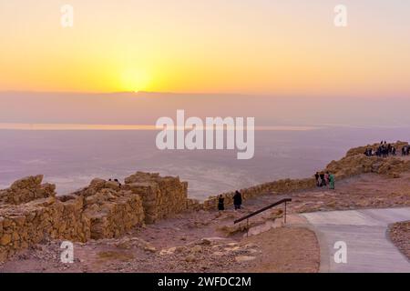 Masada, Israel - 19. Januar 2024: Blick auf die Ruinen der Festung Masada bei Sonnenaufgang, mit Besuchern, und das Tote Meer im Hintergrund, Judäische Wüste Stockfoto