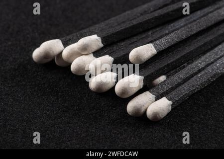 Schwarze hölzerne Streichhölzer auf schwarzem Hintergrund. Streichhölzer mit hellblauen Köpfen Makro. Verstreute hölzerne Streichhölzer ohne Box-Nahaufnahme. Designelement für Stockfoto