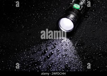 Taschenlampe wasserdicht in Tropfen auf schwarzem Hintergrund. Stockfoto