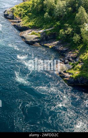 Vertikaler Blick auf die gewaltigen Whirlpools von Saltstraumen neben der üppigen Küste, eine atemberaubende Darstellung der Gezeitenmacht Norwegens Stockfoto