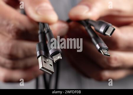 Hände halten das Universal-Adapterkabel von USB-Anschluss zu Micro-USB-, Mini-USB- und anderen Anschlüssen. Stockfoto