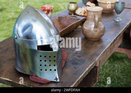 Mittelalterlicher Ritterhelm am Rand eines Holztisches Stockfoto