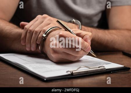 Steuerflucht, Kriminalität und Betrug. Mann in Handschellen ausfüllen der Steuerformulare Einkommensteuererklärungen und Handschellen Stockfoto