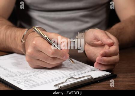 Steuerflucht, Kriminalität und Betrug. Mann in Handschellen ausfüllen der Steuerformulare Einkommensteuererklärungen und Handschellen Stockfoto