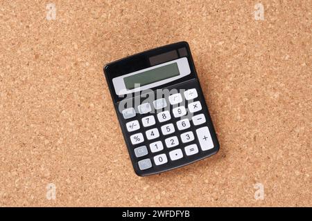 Taschenrechner und Stift auf einer Korkplatte, Nahaufnahme. Stockfoto