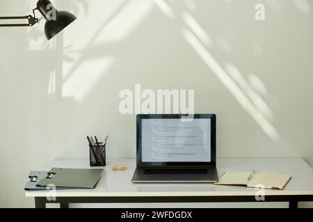 Geöffnetes Notebook mit Programmiercode auf dem Bildschirm auf dem Schreibtisch eines Freelancers Stockfoto