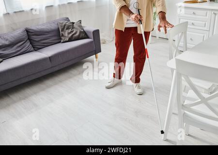 Zugeschnittene Ansicht eines blinden indianers in lässiger Kleidung mit seinem Gehstock in der Küche Stockfoto