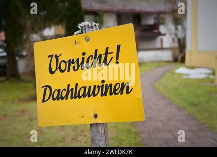 Schild mit der deutschen Inschrift Vorsicht Dachlawinen vor einer Kirche in Inzell in Bayern. Übersetzung: Vorsicht vor Dachlawinen Stockfoto