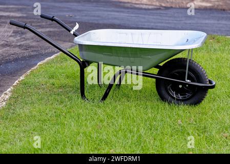 Grüne Schubkarre im Garten - Schubkarre auf grünem Gras Stockfoto