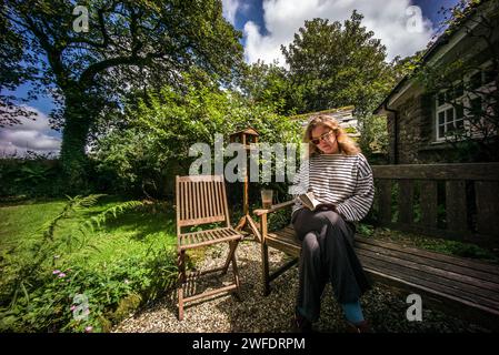 Frau sitzt auf der Gartenbank und liest Stockfoto