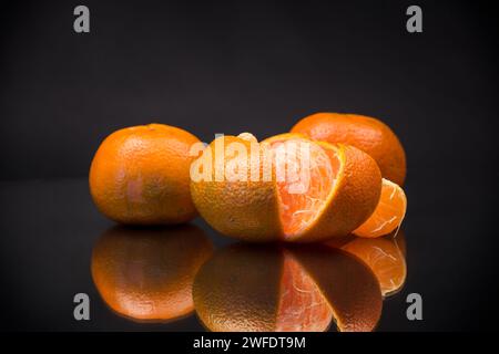 Reife Mandarinen mit Schale isoliert auf schwarzem Hintergrund Stockfoto