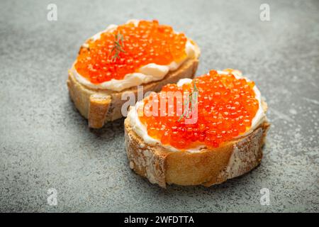 Zwei Kaviar-Toasts Baguette Canapé mit Butter und rotem Lachs Kaviar von oben auf grauem Betonhintergrund, festliche Luxus-Delikatesse und Vorspeise Stockfoto