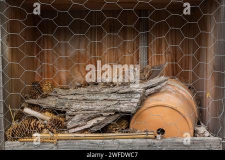 Bughotel aus Baumrinde, Tannenzapfen und Blumentopf für Insekten, in denen sie sich während der Wintermonate verstecken und überwintern können. Stockfoto