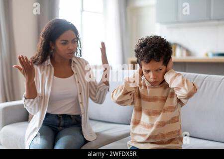 Familienargument. Der schwarze Junge hat die Ohren verdeckt, nicht um Mutters Schimpfungen zu hören Stockfoto