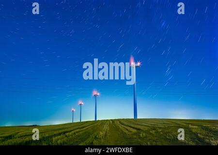 Sternenklare Nacht über spanischen Windmühlen - Eine faszinierende Langzeitaufnahme, die die heitere Schönheit von Windturbinen vor der Kulisse von Sternenpfaden einfängt Stockfoto