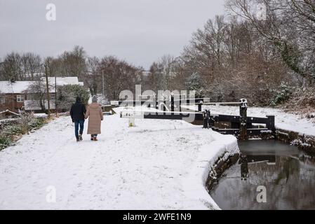 Ein Paar spazieren am Peak Forest Canal bei Marple an einem schneebedeckten Januarmorgen. Greater Manchester, England. Stockfoto