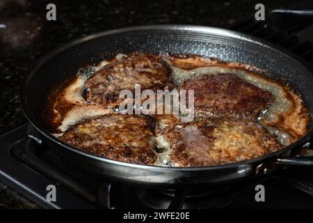Schnitzel in einer Pfanne auf dem Gasherd braten. Hausmannskonzept. Stockfoto