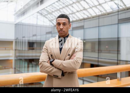 Geschäftsmann, der in die Kamera schaut, während er allein an einem modernen Arbeitsplatz steht. Hochwertige Fotos Stockfoto