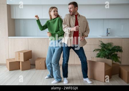 Überglücklich tanzende Mann und Frau ziehen in eine neue Wohnung, glücklich über das Zusammenleben. Umzug Stockfoto