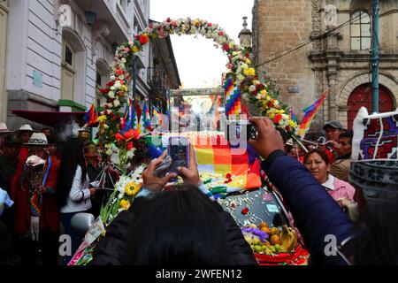 La Paz, BOLIVIEN; 24. Januar 2015. Die Menschen fotografieren mit ihrem Smartphone eine antike Ille (oder Statue) eines Ekeko (ein Gott der Aymara), während dieser durch die Straßen von La Paz gleitet, um seinen ersten Auftritt beim Alasitas-Festival zu feiern, das heute beginnt. Die Statue ist etwa 2000 Jahre alt und wurde von der Pucara-Kultur hergestellt. Sie wurde 1858 von der archäologischen Stätte Tiwanaku in die Schweiz gebracht und im November 2014 vom Geschichtsmuseum Bern nach Bolivien zurückgegeben. Auf der rechten Seite befindet sich ein Teil der Kirche San Francisco. Stockfoto