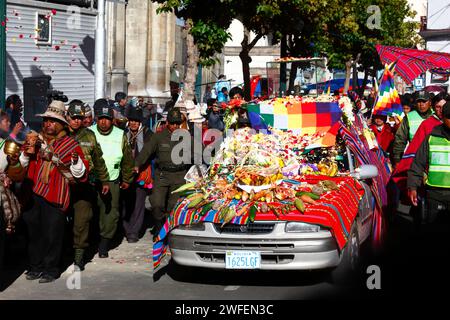 La Paz, BOLIVIEN; 24. Januar 2015. Die bolivianische Polizei eskortiert eine antike illa (oder Statue) eines Ekeko (ein Gott des Überflusses der Aymara), während sie auf einem dekorierten Auto durch die Straßen von La Paz gleitet, um ihren ersten Auftritt beim Alasitas-Festival zu feiern, das heute beginnt. Die Statue ist etwa 2000 Jahre alt und wurde von der Pucara-Kultur hergestellt. Sie wurde 1858 von der archäologischen Stätte Tiwanaku in die Schweiz gebracht und im November 2014 vom Geschichtsmuseum Bern nach Bolivien zurückgegeben. Stockfoto