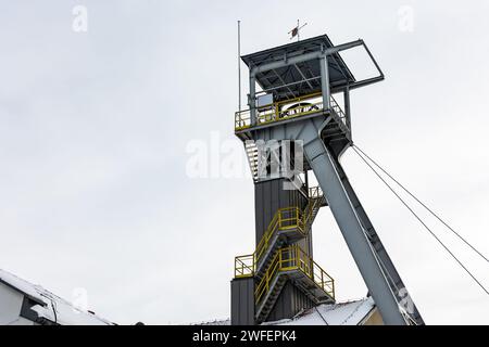 Ein Bergwerksschacht gegen einen grauen Himmel. Nahaufnahme der Räder oben auf der Welle. Stockfoto