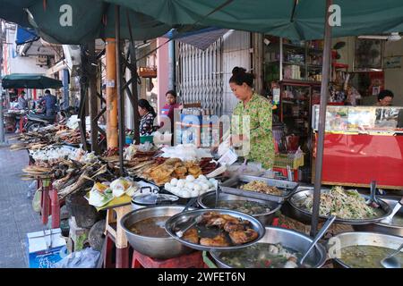 Frau, die Essen und andere billige Sachen auf der Straße in Downtown Phnom Penh, Kambodscha verkauft Stockfoto