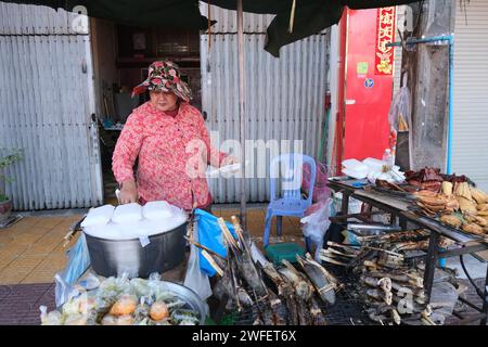 Frau, die Essen und andere billige Sachen auf der Straße in Downtown Phnom Penh, Kambodscha verkauft Stockfoto