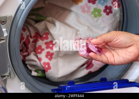 Frau, die den Wäschetopf in die elektrische Waschmaschine bringt. Haushaltsgeräte Stockfoto