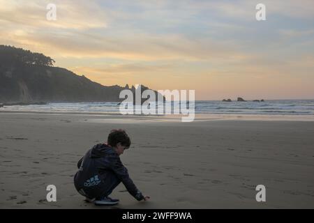 Aguilar Beach, Muros de Nalon, Spanien; 09 09 2023 : Junge schreibt in der Sonne bei Sonnenuntergang Stockfoto