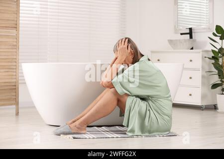 Wechseljahre. Deprimierte Frau in der Nähe der Badewanne im Badezimmer Stockfoto