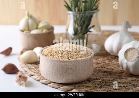 Getrocknete Knoblauchkörner in der Schüssel, frische Zwiebeln und Nelken auf weißem Tisch Stockfoto