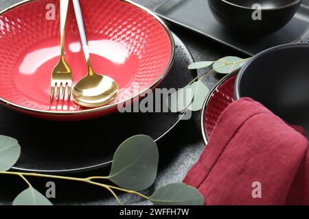 Stilvolle Keramikteller, Besteck und Blumendekor auf grauem Tisch, Nahaufnahme Stockfoto