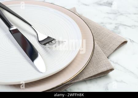 Teller, Besteck und Serviette auf weißem Tisch reinigen, Nahaufnahme Stockfoto